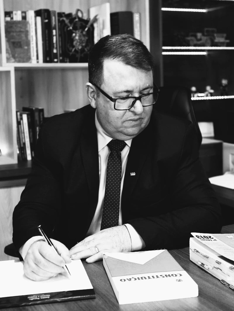 Jair de Souza trabalhando em sua mesa, com a Constituição e a CLT abertas